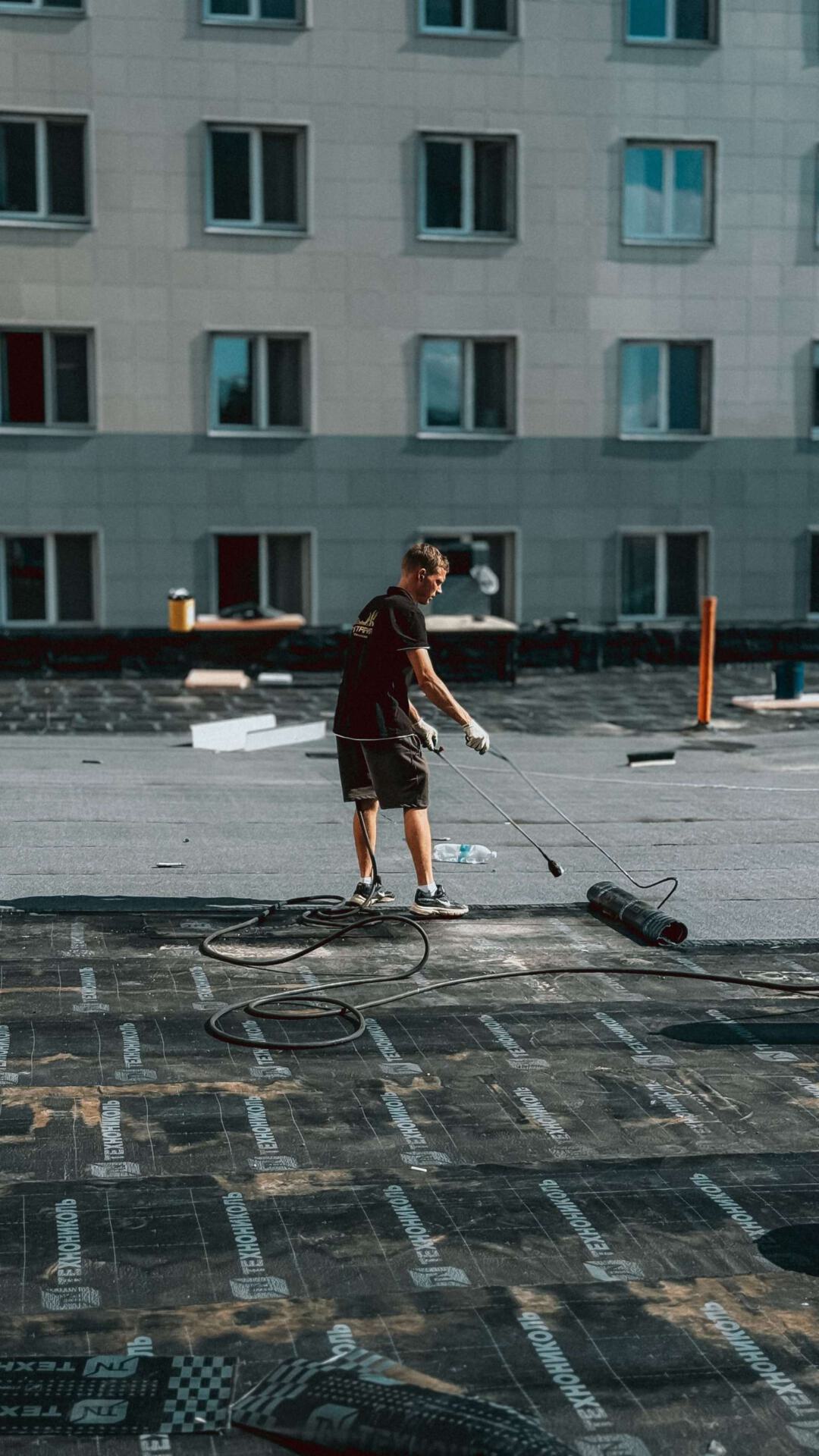 Bauarbeiter trägt Dachmaterial auf einem Gebäudedach auf